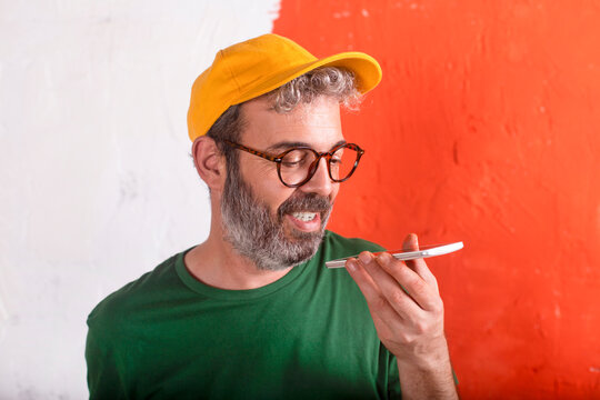 Portrait of man using smartphone in front of orange wall - Powered by Adobe