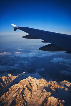 France, Auvergne-Rhone-Alpes, Wing of Airbus A321 flying over European Alps and Lake Geneva at dawn