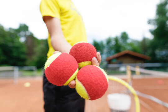 Boy on the tennis court, holding tennis balls