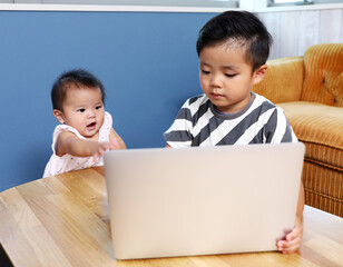 パソコンの画面を見ている二人の子供。兄と妹。