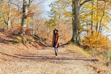 Mature woman wearing hat and jacket walking on forest path
