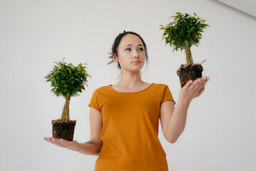Young woman holding two bonsai trees
