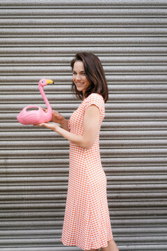Woman in summer dress with heart pattern, holding pink flamingo figure