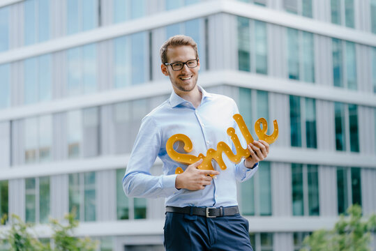 Young businessman holding smile sign