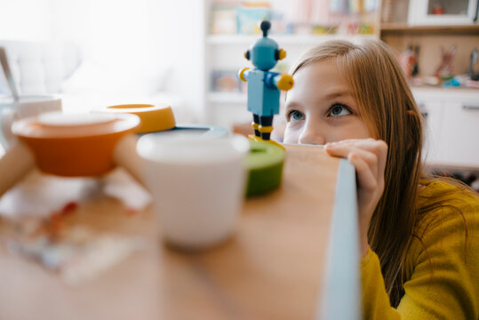 Girl at home looking at toy robot