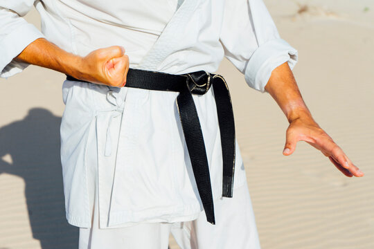 Close-up of mature man practicing karate while standing at beach