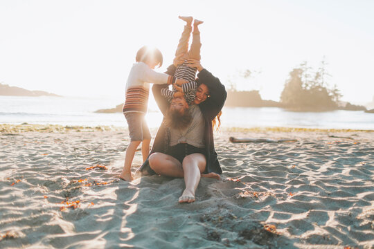 Mother playing with children while sitting on sand at beach