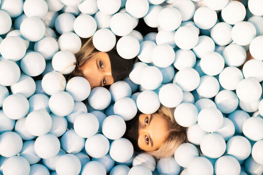 Friends wearing face masks lying in ball pool