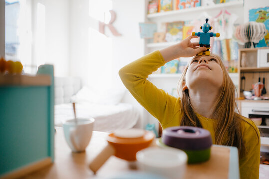 Girl at home playing with toy robot