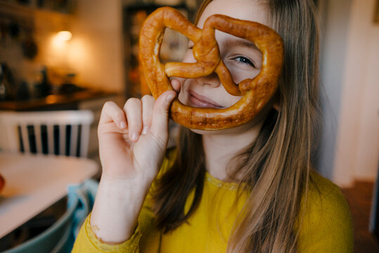 Girl in kitchen holding pretzel