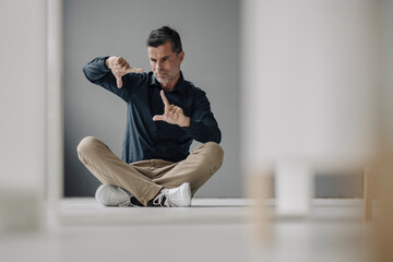 Mature businessman sitting on the floor gesturing