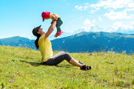 Playful mother with her child playing over grass at Col des Aravis, Haute-Savoie, France