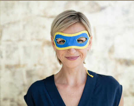 Portrait of blond businesswoman, wearing superwoman mask