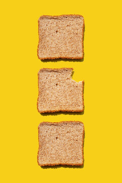 Studio shot of three slices of wheat bread against yellow background