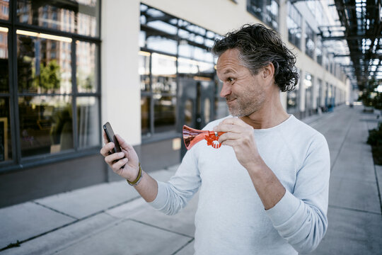 Portrait of mature man with horn and smartphone