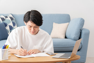 パソコンを見て勉強する若い男性・オンライン授業
