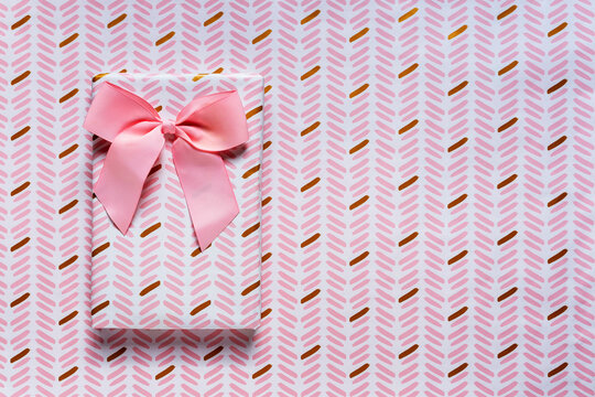 Pink wrapped gift against wrapping paper background