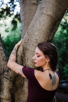 Portrait of young woman hugging tree in park