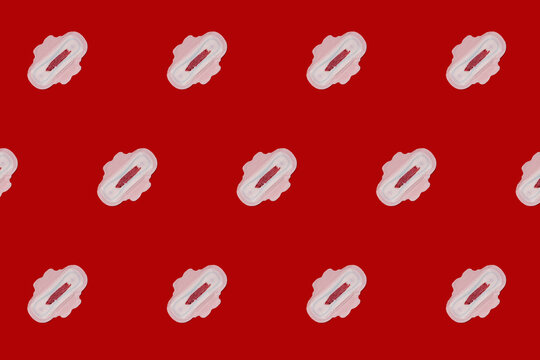 Pattern of bloodstained sanitary pads against red background