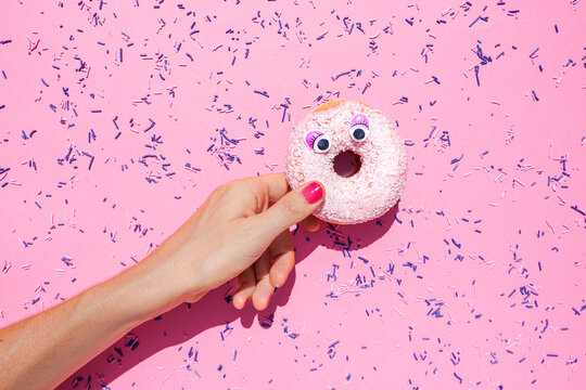 Hand of woman holding sweet doughnut with googly eyes - Powered by Adobe
