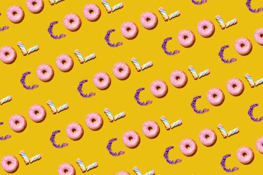 Pattern of doughnuts, marshmallows and sugar sprinkles arranged into single repeated word