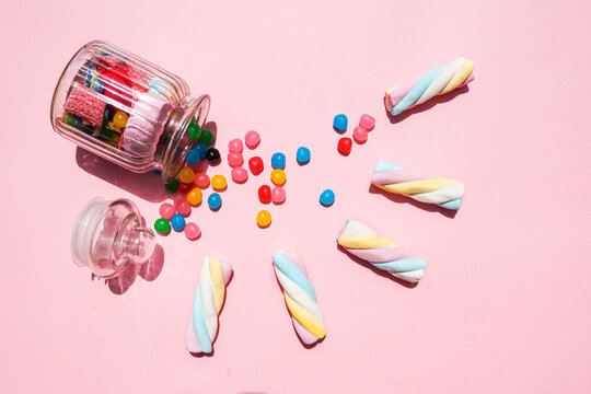 Studio shot of twisted marshmallows and candies spilling out from toppled jar