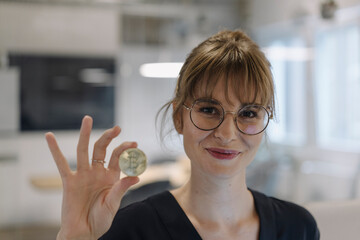 Portrait of businesswoman holding bitcoin in office