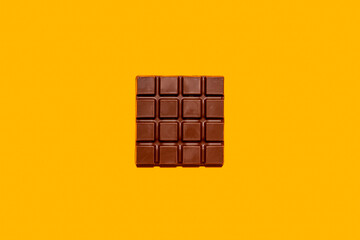 Studio shot of milk chocolate bar against yellow background