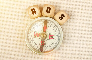 On the table is a compass and cubes with the inscription - ROS