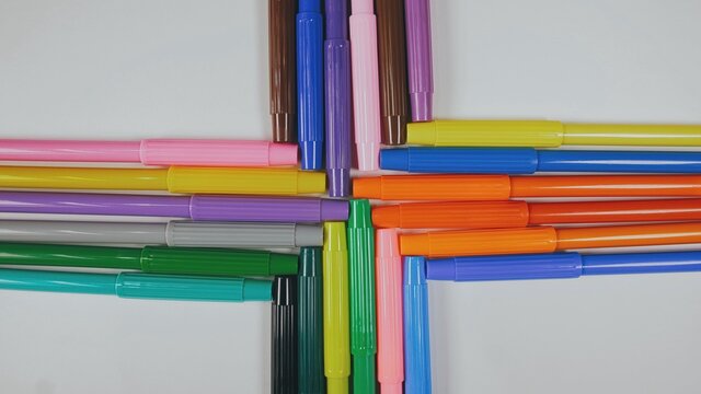 Many colored pencils are arranged around the edges of the image as a frame. In the center is an empty background with space for text. Mock up with copy space.
