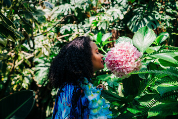 African woman wearing floral garland smelling flower at public park