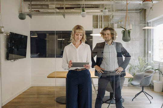 Businessman and businesswoman using tablet in office