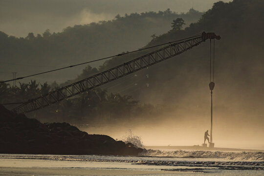 Indonesia, Sumbawa Island, Man and construction crane at seaside