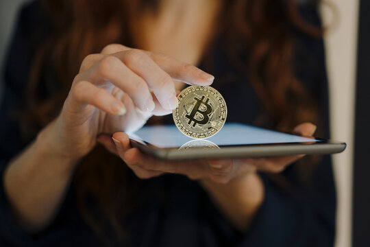 Close-up of woman holding bitcoin and tablet