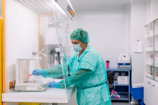 Female scientist measuring powder medicine on scale in laboratory