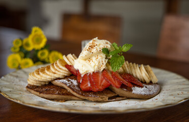 Gluten free pancakes with banana, strawberry and whipped cream. Healthy and delicious dessert. Close up view