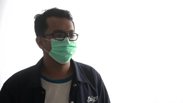 high key video of a young man wearing a mask with glasses while operating a thermogun