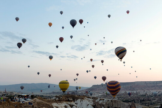 Colorful hot air balloons flying over landscape against sky in Turkey during sunset, Cappadocia