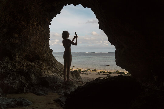 Young woman in cave, taking a photo