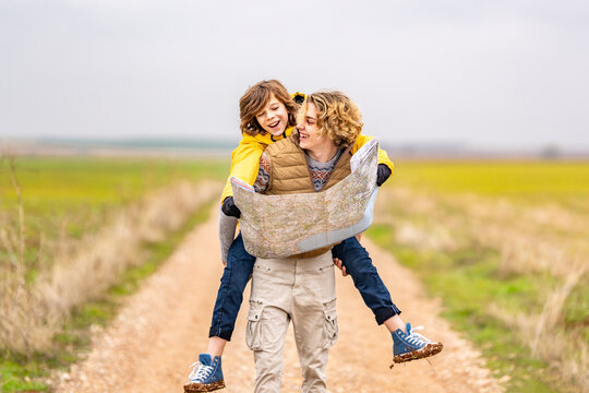 Young man piggybacking younger brother during hike
