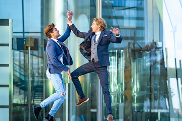 Excited business people giving high five while jumping against glass