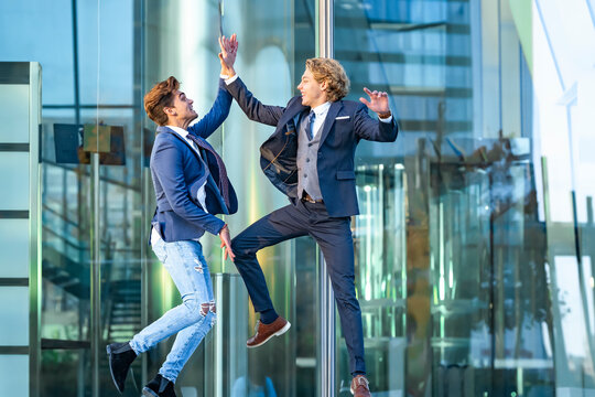 Excited Business People Giving High Five While Jumping Against Glass