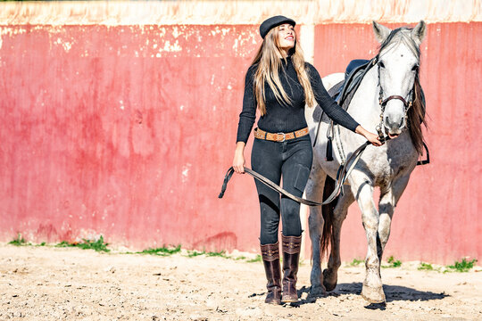 Woman walking with horse in paddock