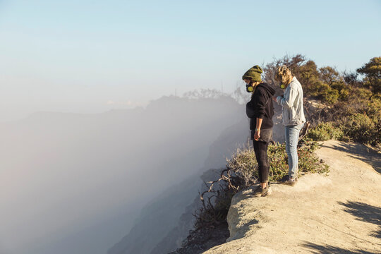 Young women with respirator masks standing at the edge of volcano Ijen, Java, Indonesia