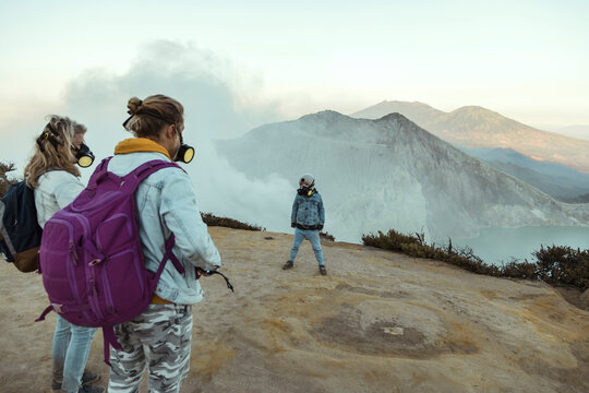 Family with respirator masks standing at the edge of volcano Ijen, Java, Indonesia