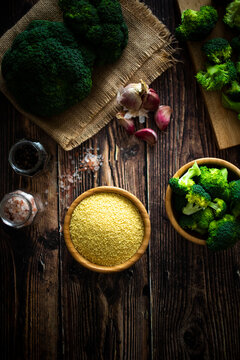 Salt and pepper, garlic, bowl of couscous and chopped broccoli