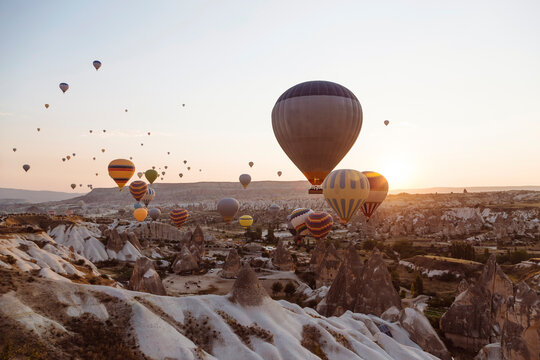 Hot air balloons flying over rocky landscape against clear sky in Goreme during sunset, Cappadocia, Turkey