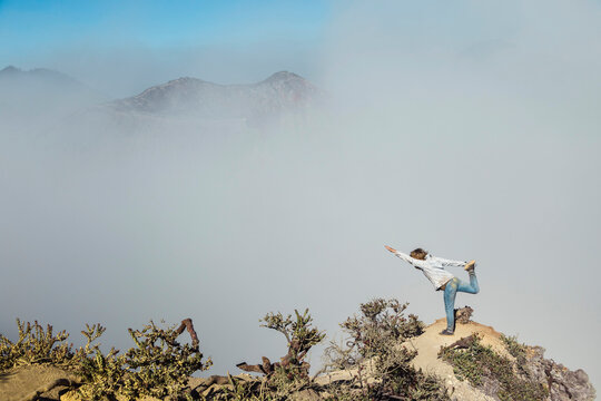 Woman practising yoga on viewpoint, near Ijen volcano, Java, Indonesia