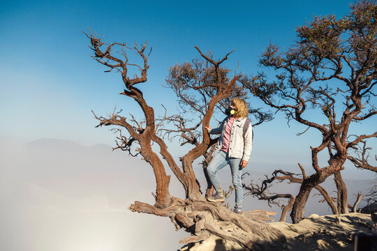 Woman with respirator mask on a tree at volcano Ijen, Java, Indonesia