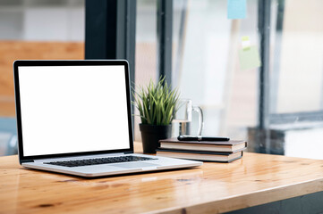 Fototapeta premium Mockup blank screen laptop computer on wooden table in co-workspace.
